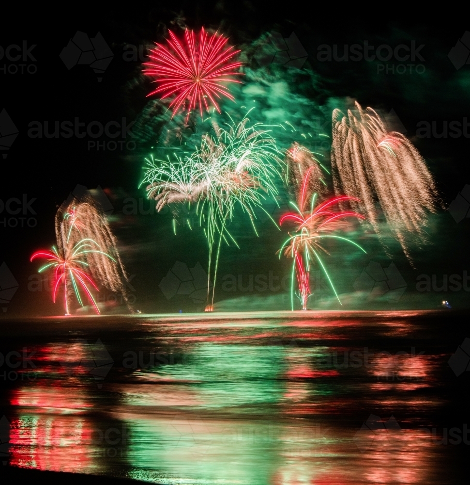 Multi coloured fireworks exploding over an ocean in the night sky. - Australian Stock Image