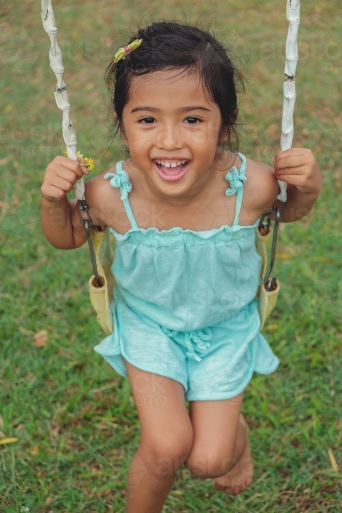 Multi Ethnic little girl on swing - Australian Stock Image