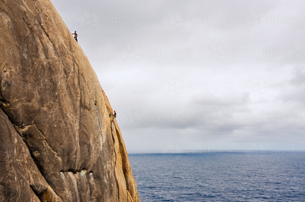 Multi pitch rock climbing over the ocean - Australian Stock Image
