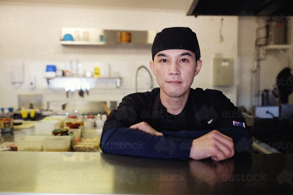 Multicultural Asian chef in Thai small business restaurant - Australian Stock Image