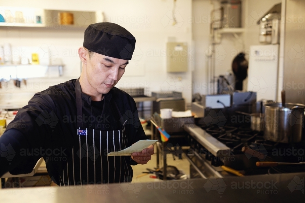 Multicultural Asian chef in Thai small business restaurant - Australian Stock Image