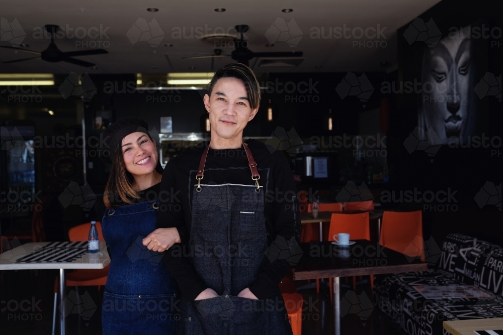 Multicultural Asian small business owners greeting in front of Thai restaurant - Australian Stock Image