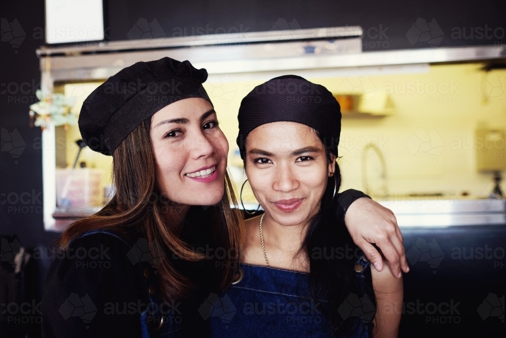 Multicultural Asian small business owners/ waitress in Thai restaurant - Australian Stock Image