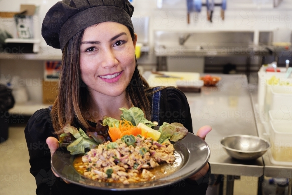 Multicultural Asian waitress with Thai food at Thai restaurant - Australian Stock Image