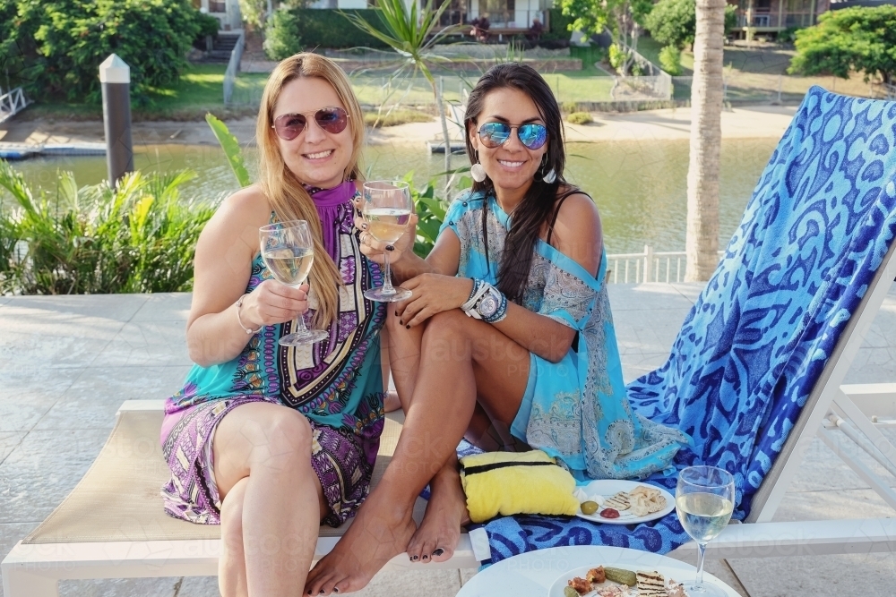 Multicultural female friends relaxing by the poolside - Australian Stock Image