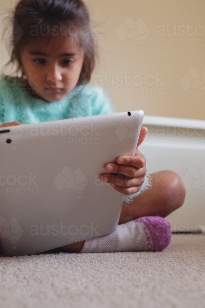 Multicultural kid using tablet in bedroom - Australian Stock Image
