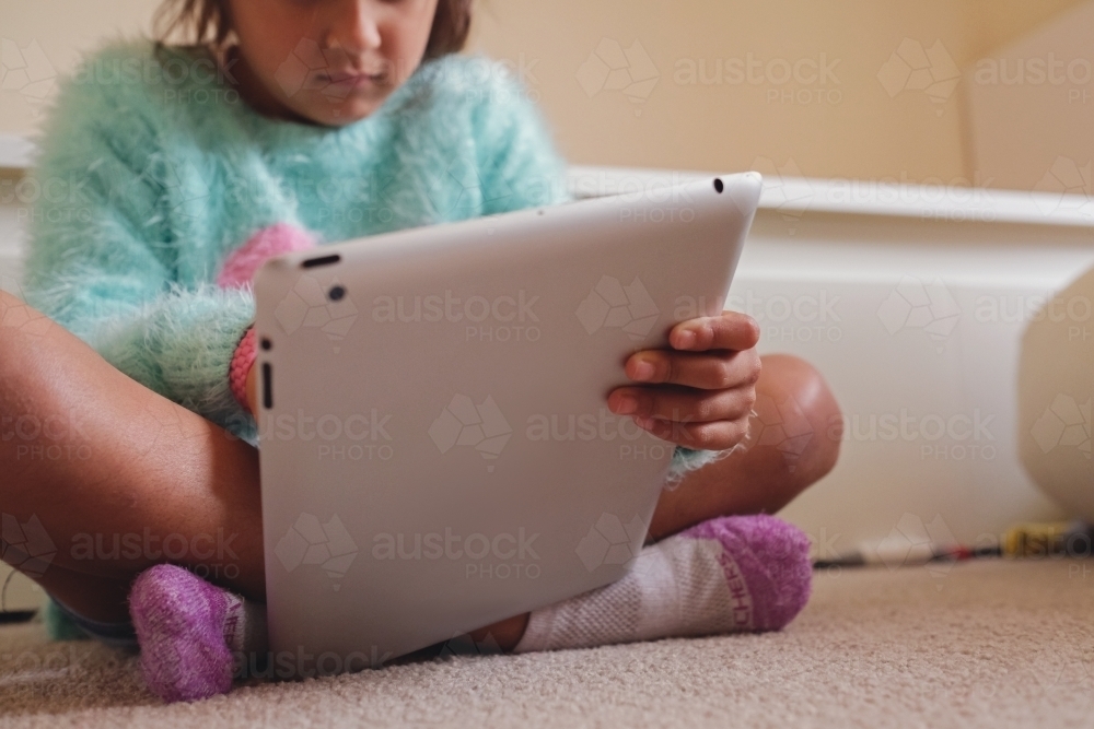 Multicultural kid using tablet in bedroom - Australian Stock Image