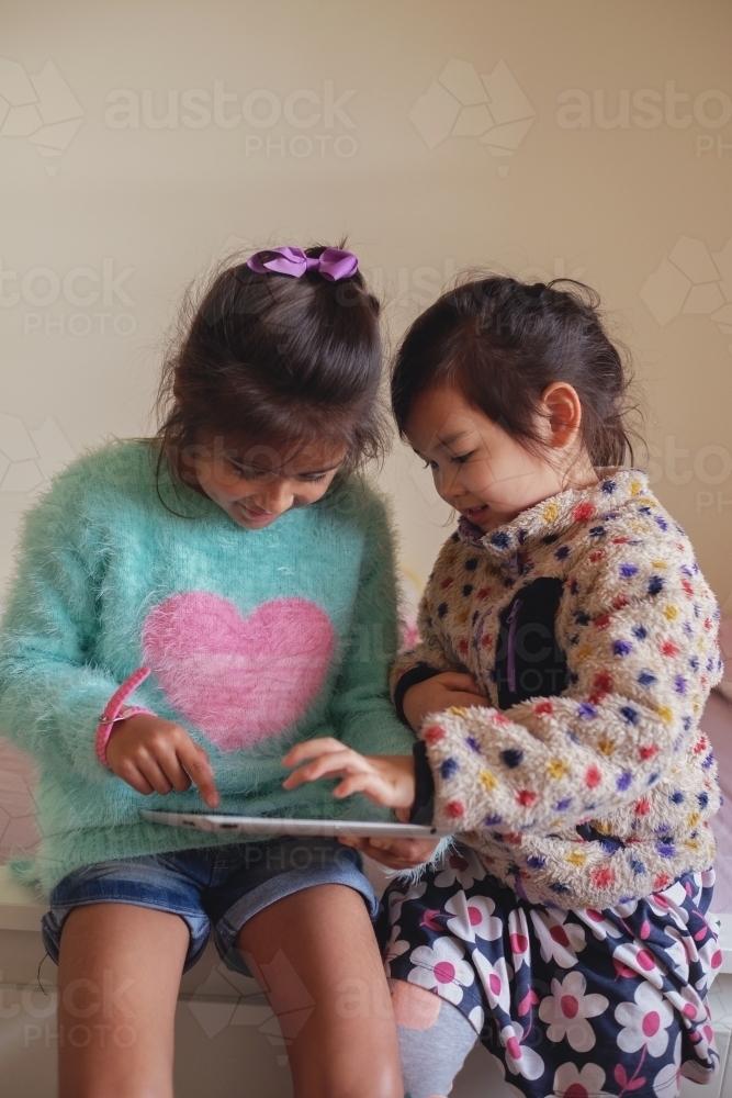 Multicultural kids using tablet in bedroom - Australian Stock Image