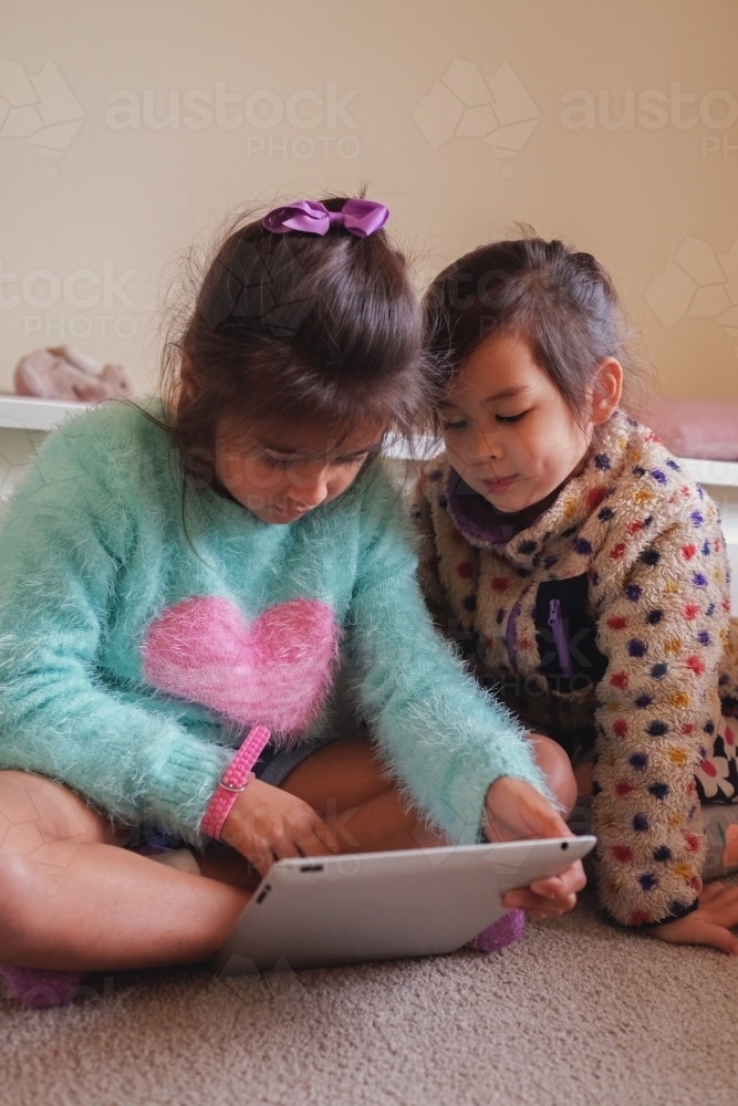Multicultural kids using tablet in bedroom - Australian Stock Image