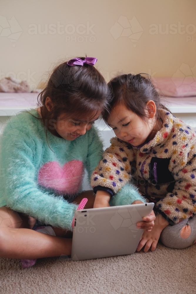 Multicultural kids using tablet in bedroom - Australian Stock Image