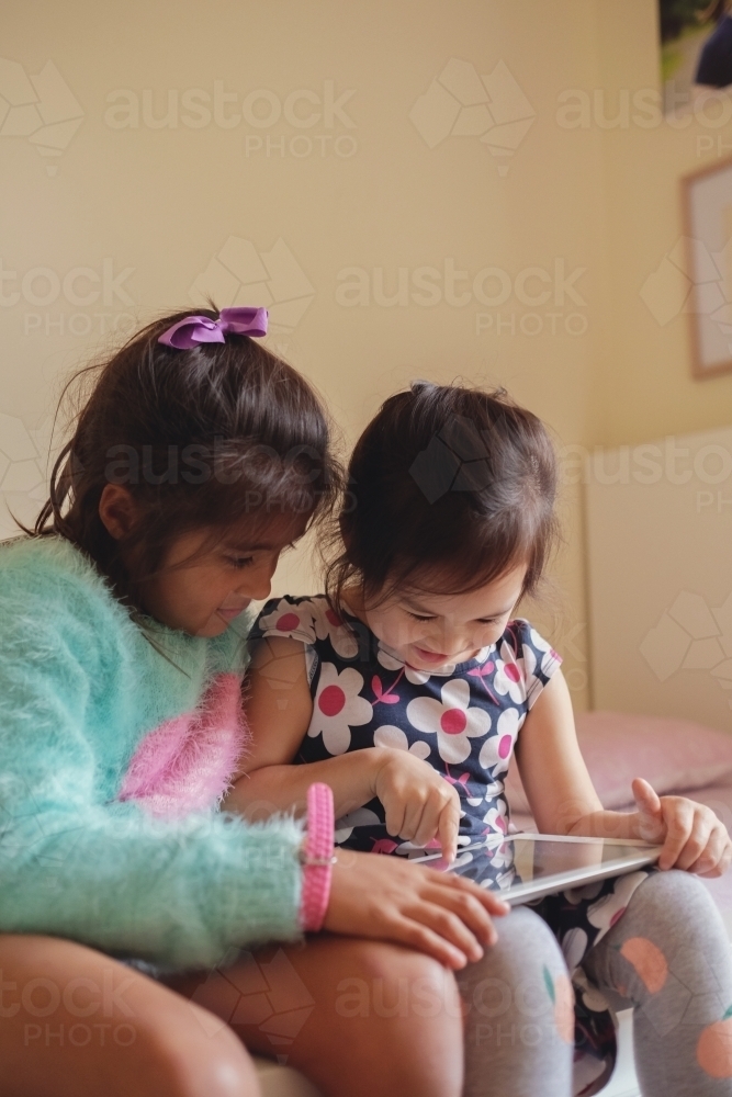 Multicultural kids using tablet in bedroom - Australian Stock Image