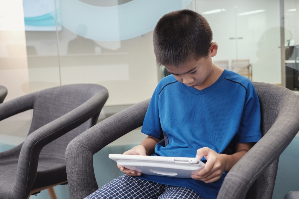 multicultural preteen boy using digital tablet - Australian Stock Image