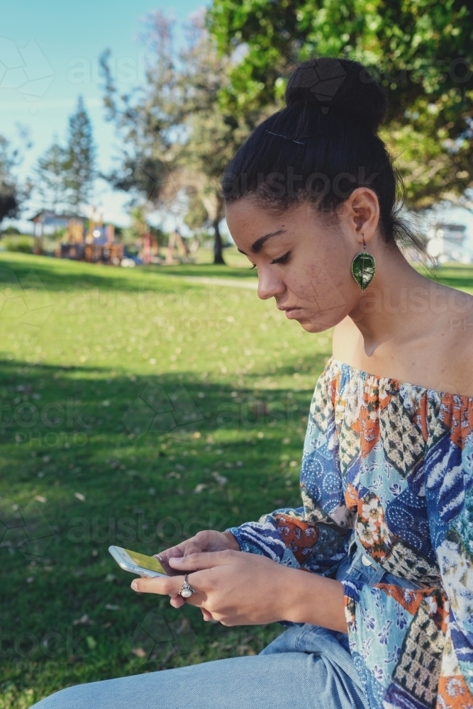 Multicultural teen girl using mobile phone - Australian Stock Image