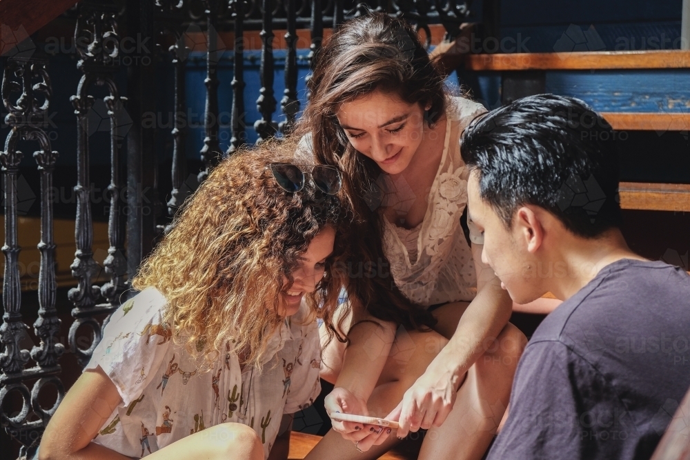 Multicultural teenagers hanging out and using mobile phone - Australian Stock Image