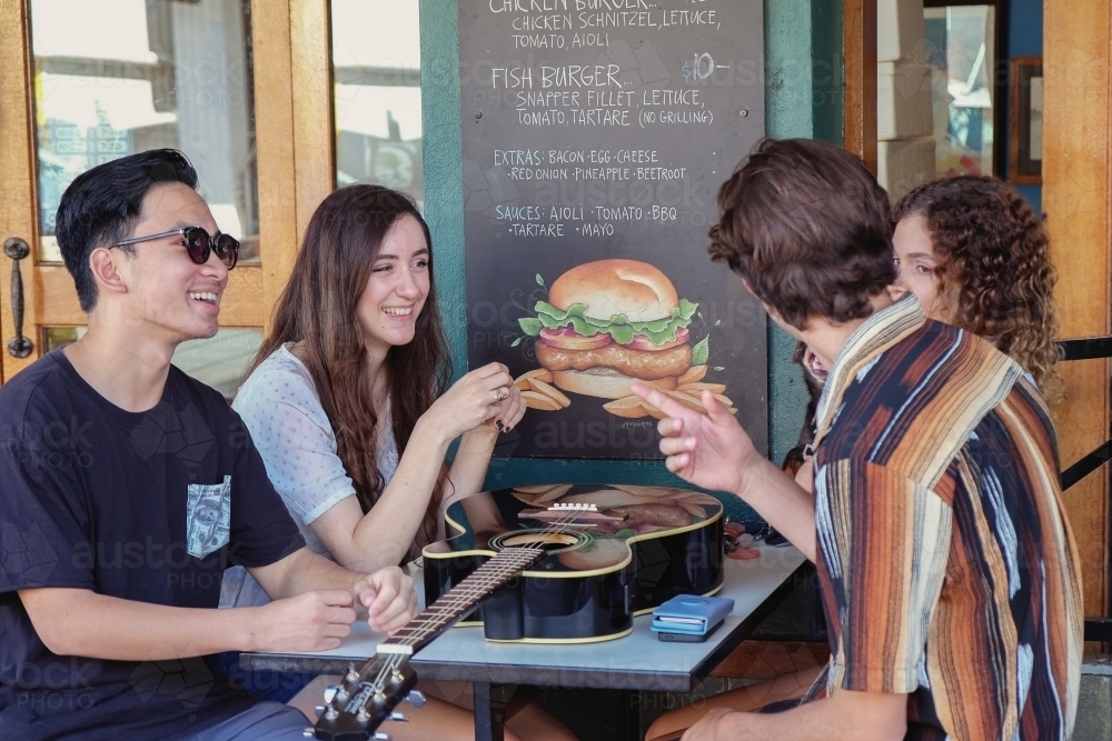 Multicultural teenagers hanging out at cafe - Australian Stock Image