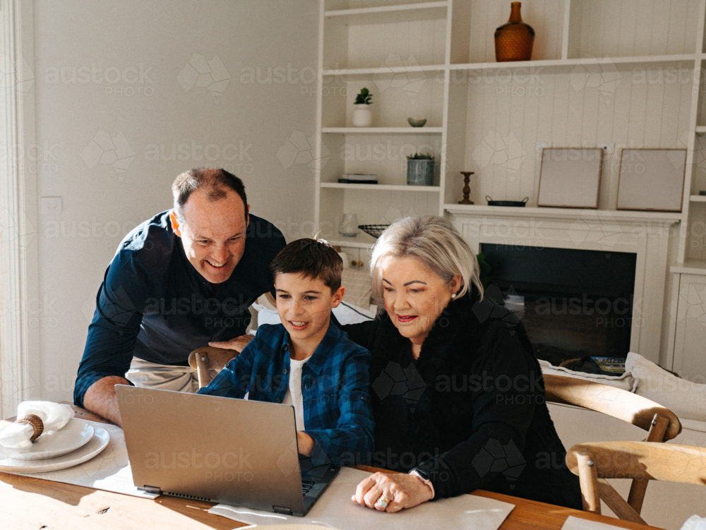 Multigeneration family working in front of a computer. - Australian Stock Image