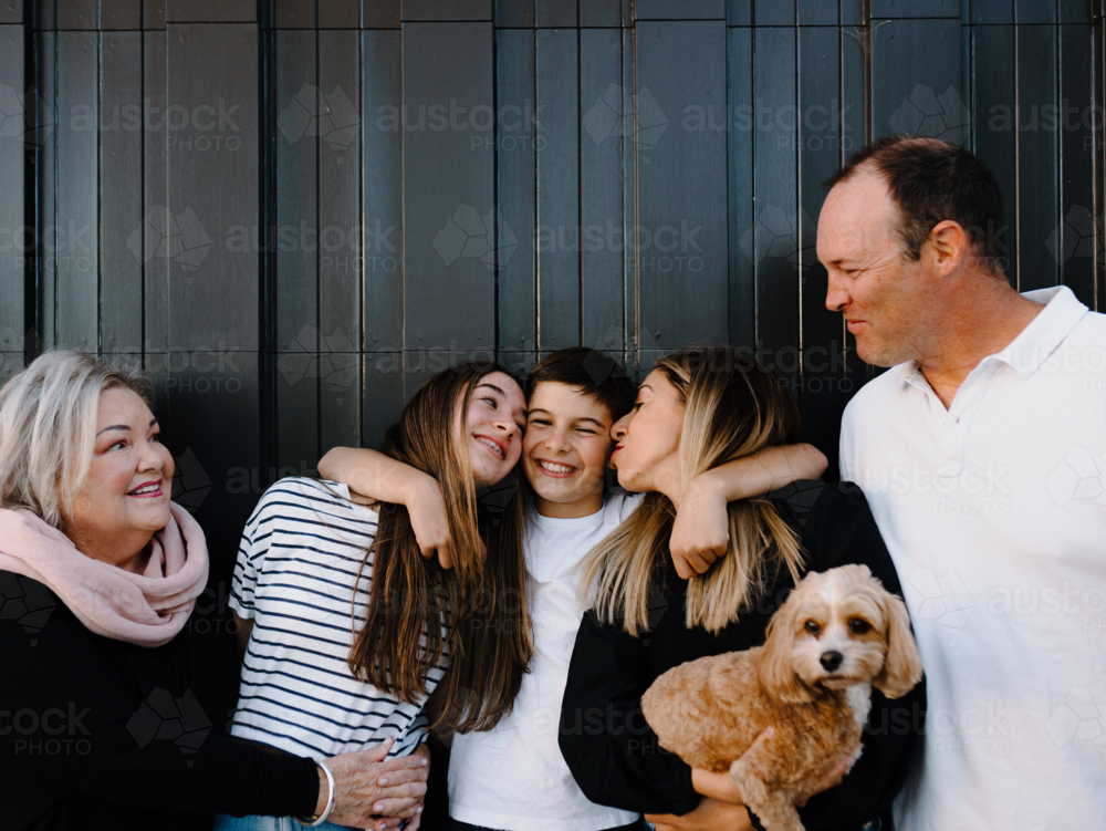 Multigenerational family standing outside in front of black garage door - Australian Stock Image