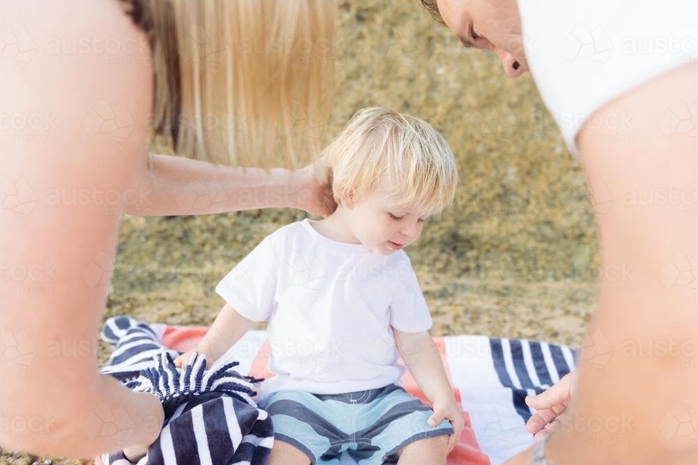 Mum and Dad fussing over young blonde boy at the beach - Australian Stock Image