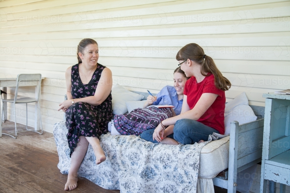 Mum and two daughters talking together on the verandah - Australian Stock Image
