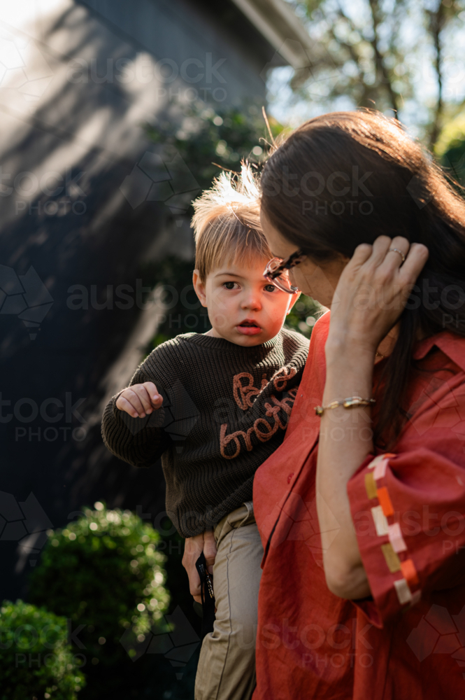 Mum holding toddler son in a sunlit garden - Australian Stock Image