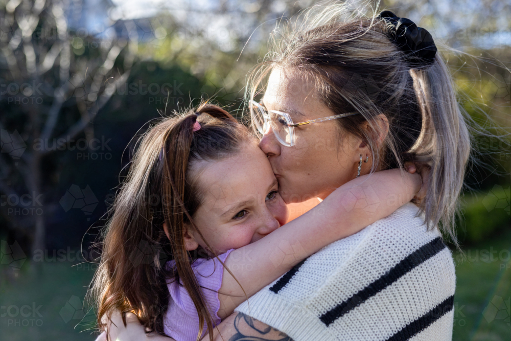 Image of Mum hugging and giving daughter a kiss in the forehead