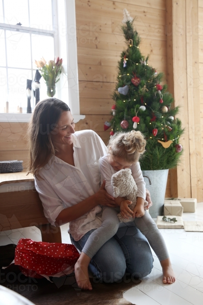 Mum laughing with daughter in front of Christmas tree - Australian Stock Image