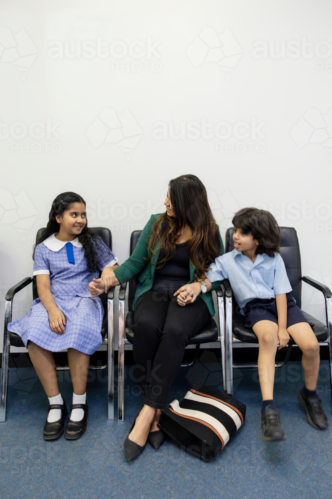 Mum waiting with kids in doctor's waiting room - Australian Stock Image