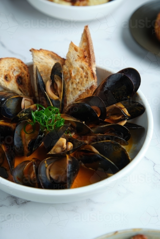 Mussels in chili curry butter with spring onion - Australian Stock Image