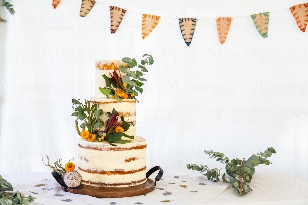 Naked wedding cake on table at Australian wedding with native greenery - Australian Stock Image