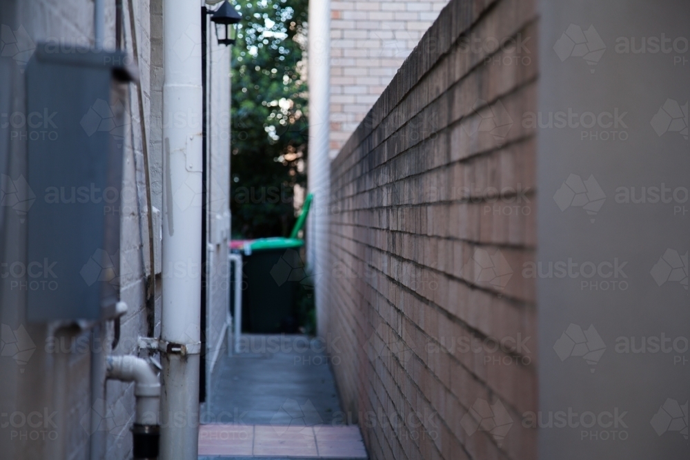 Narrow alley with bins, building and brick wall - Australian Stock Image