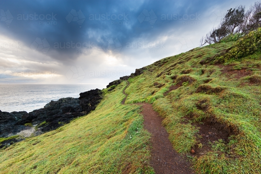 Narrow walking track on a grassy headland on an overcast day - Australian Stock Image
