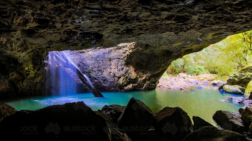 Natural Arch waterfall with river flowing through cave - Australian Stock Image