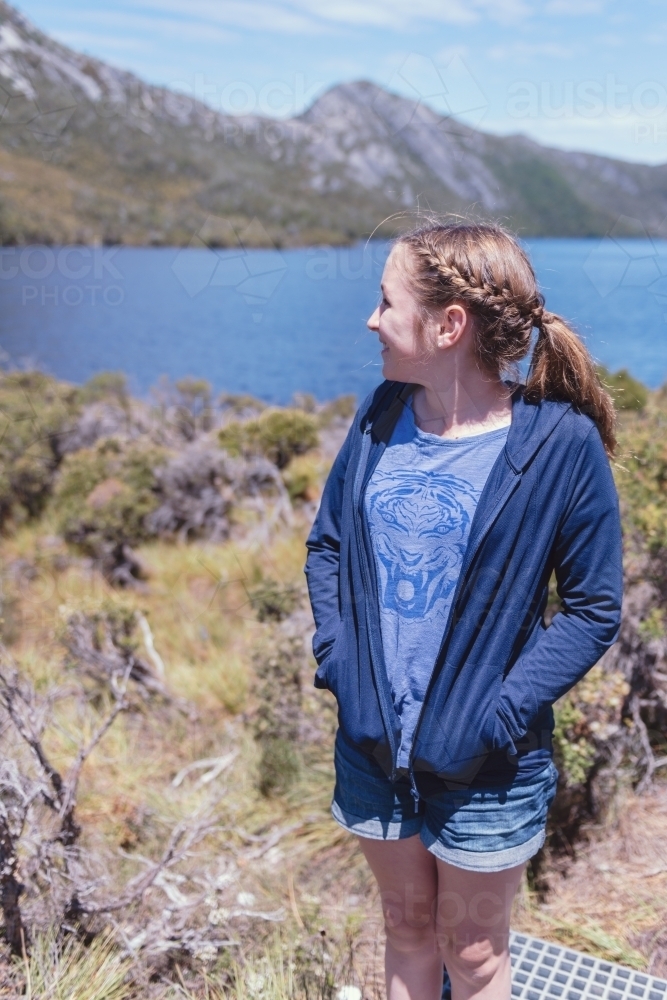 natural teen girl outdoors by a lake and mountain - Australian Stock Image
