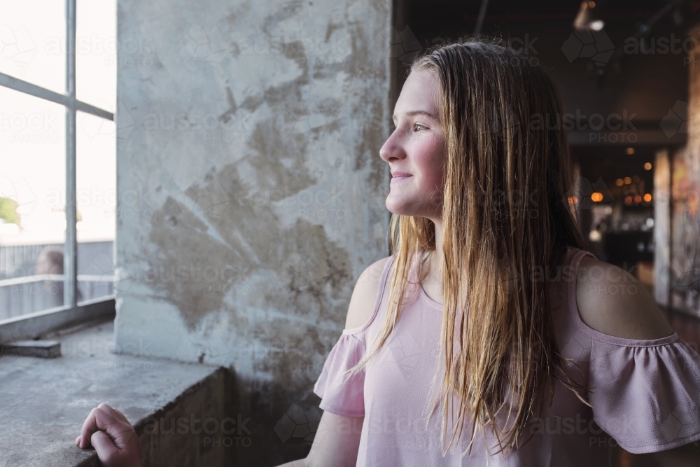 natural teen girl portrait, looking out window - Australian Stock Image