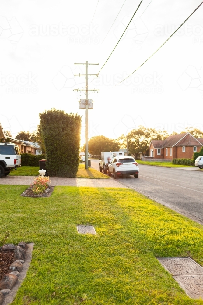 Neat and tidy lawn grass of front yard on street corner in warm sunset light - Australian Stock Image