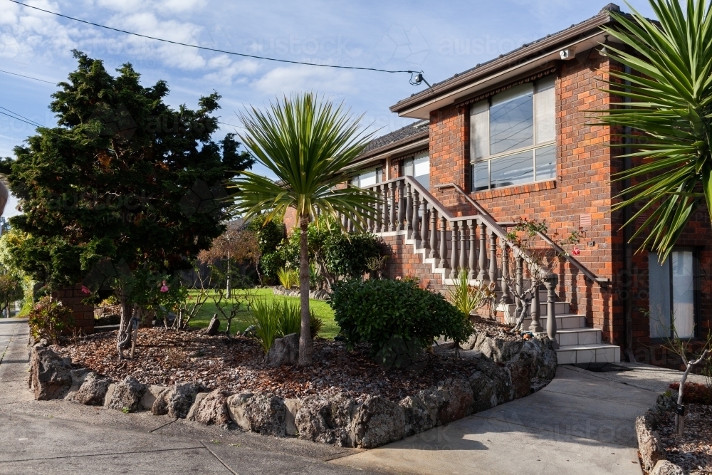 Neat front garden of two storey house with staircase to front door - Australian Stock Image