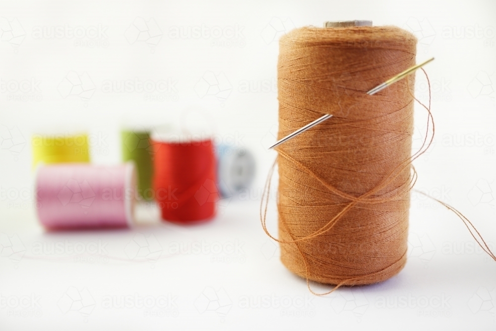 needle and thread with more cotton reels behind - Australian Stock Image