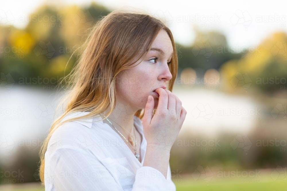 Image of nervous teen girl chewing fingernails Austockphoto