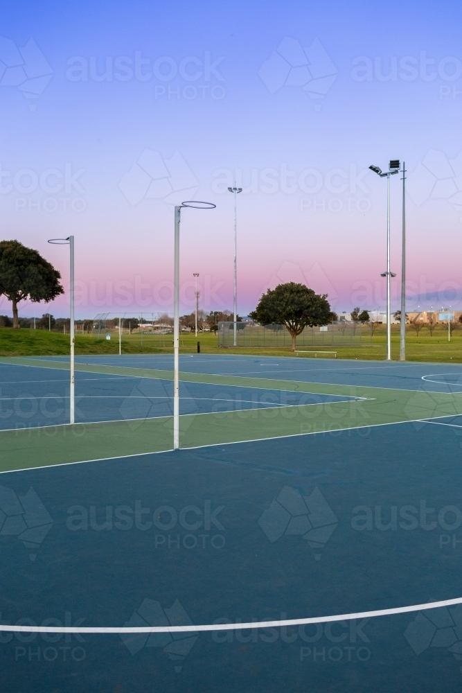 Netball hoop at empty community sports ground in dusk light - Australian Stock Image