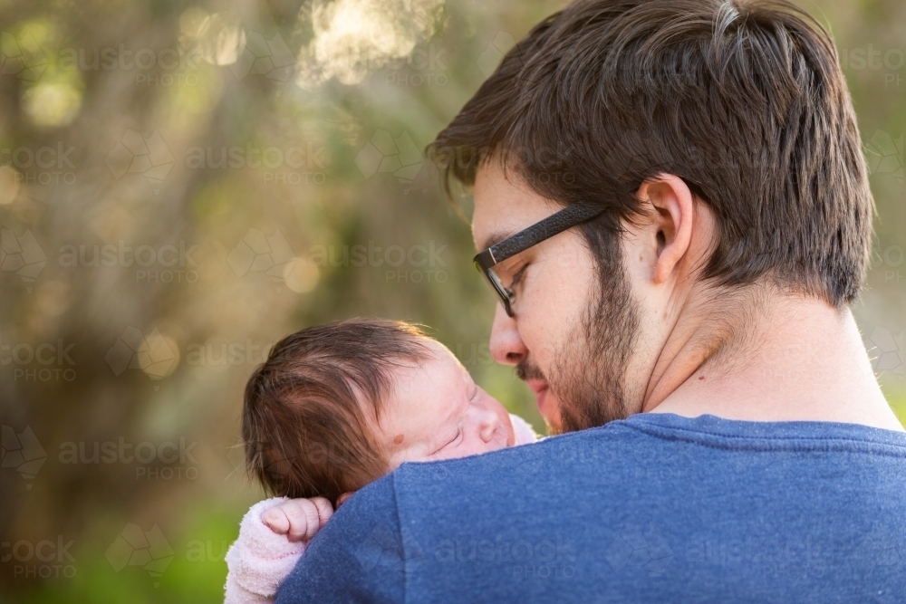 New dad holding his sleeping newborn baby daughter - Australian Stock Image