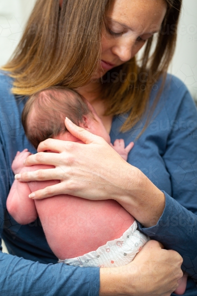 New mother cradling her baby to her chest - Australian Stock Image