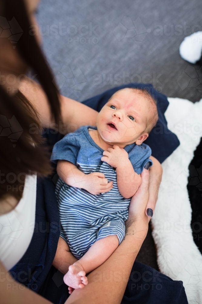 Newborn baby boy in mother's arms looking up at her - Australian Stock Image