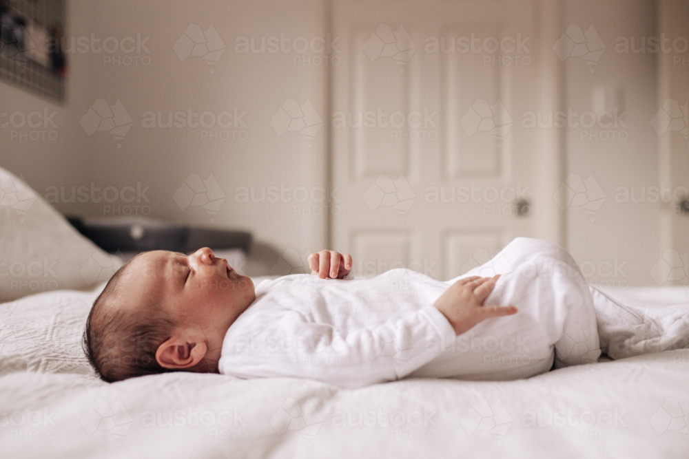 Newborn baby boy lying on his back on the bed - Australian Stock Image