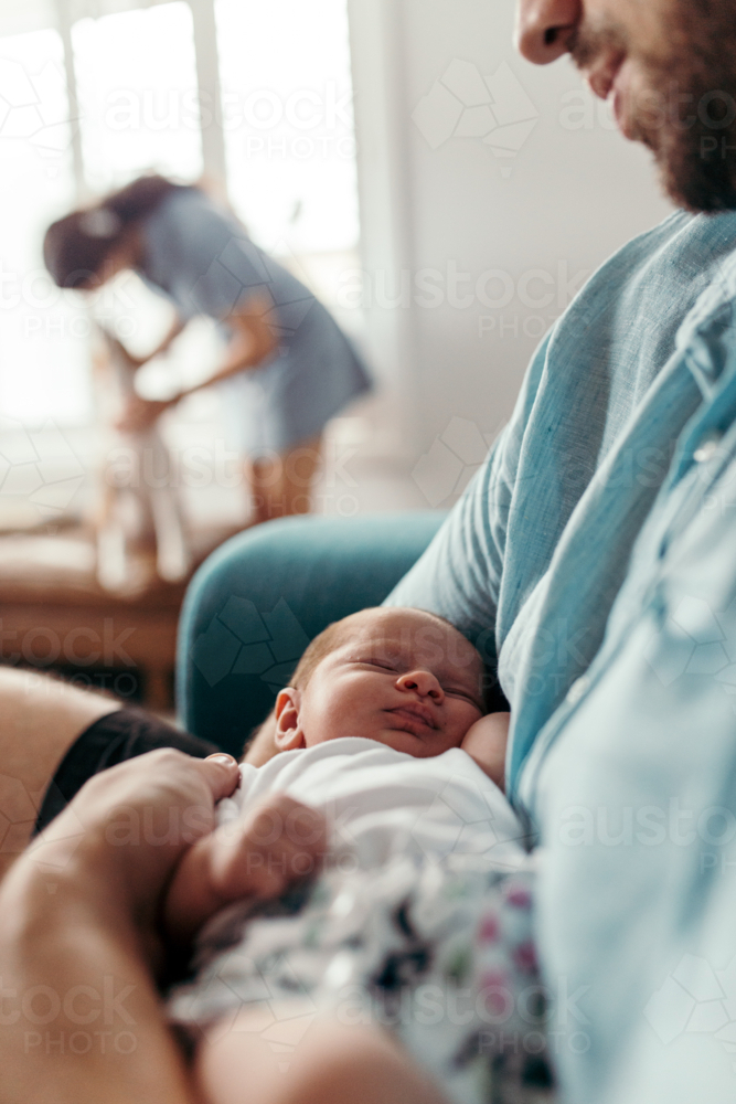 Newborn baby girl sleeping in father's arms - Australian Stock Image