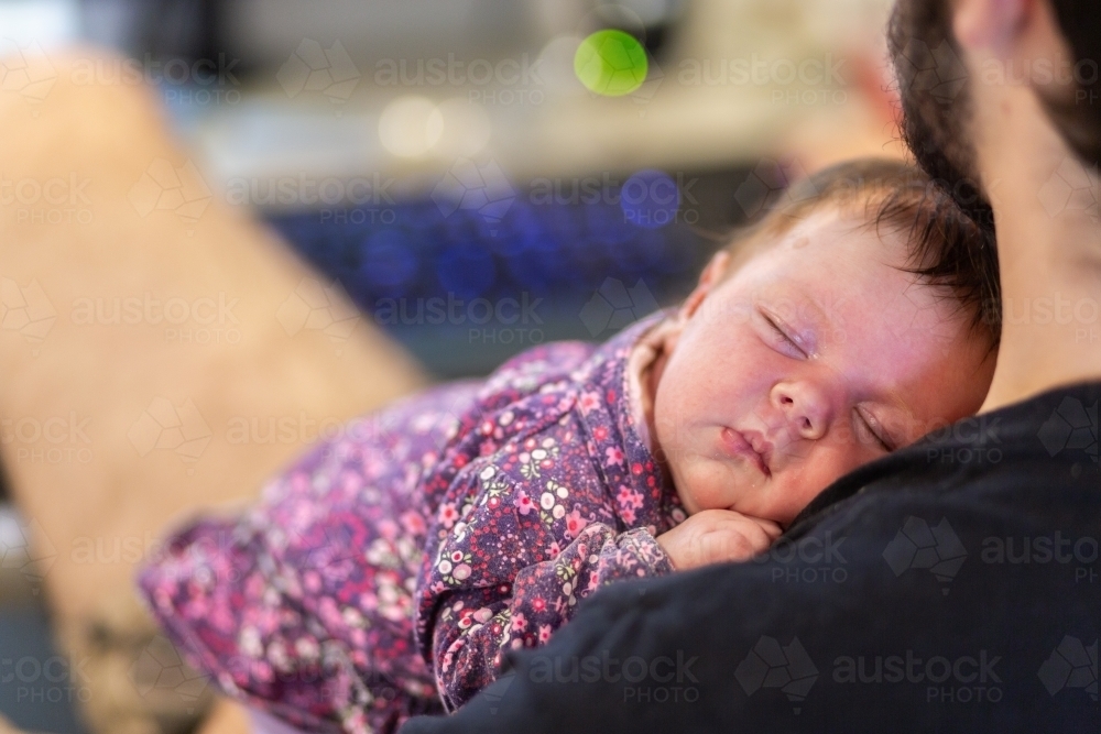 Newborn baby girl sleeping on fathers shoulder - Australian Stock Image