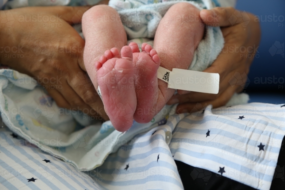 Newborn's feet with with identity tag around ankle - Australian Stock Image