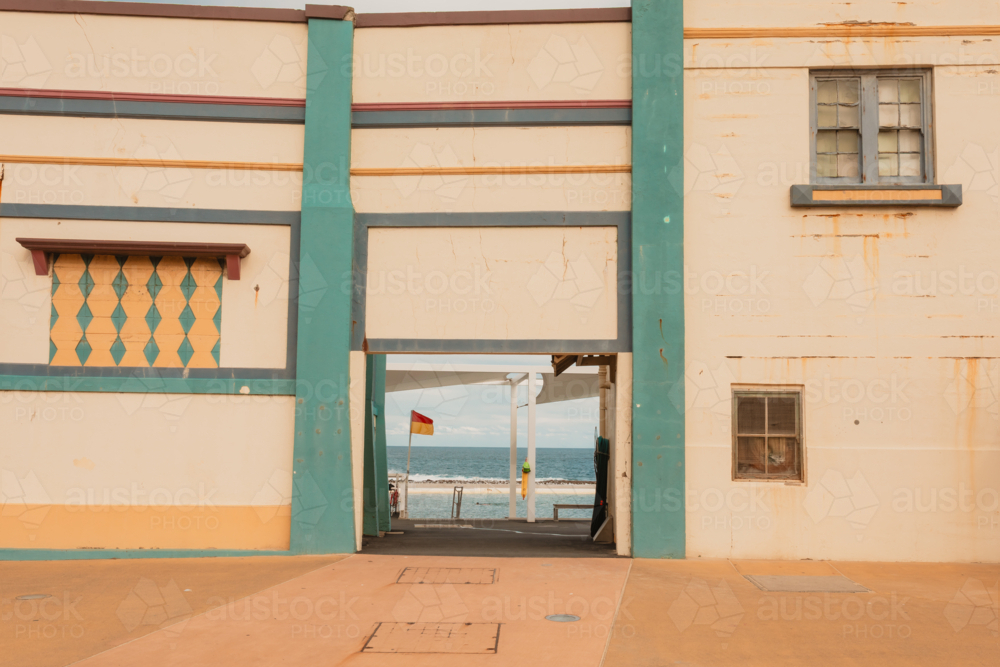 Newcastle Ocean Baths facade and front entrance with lifeguard flag, pools and ocean visible - Australian Stock Image