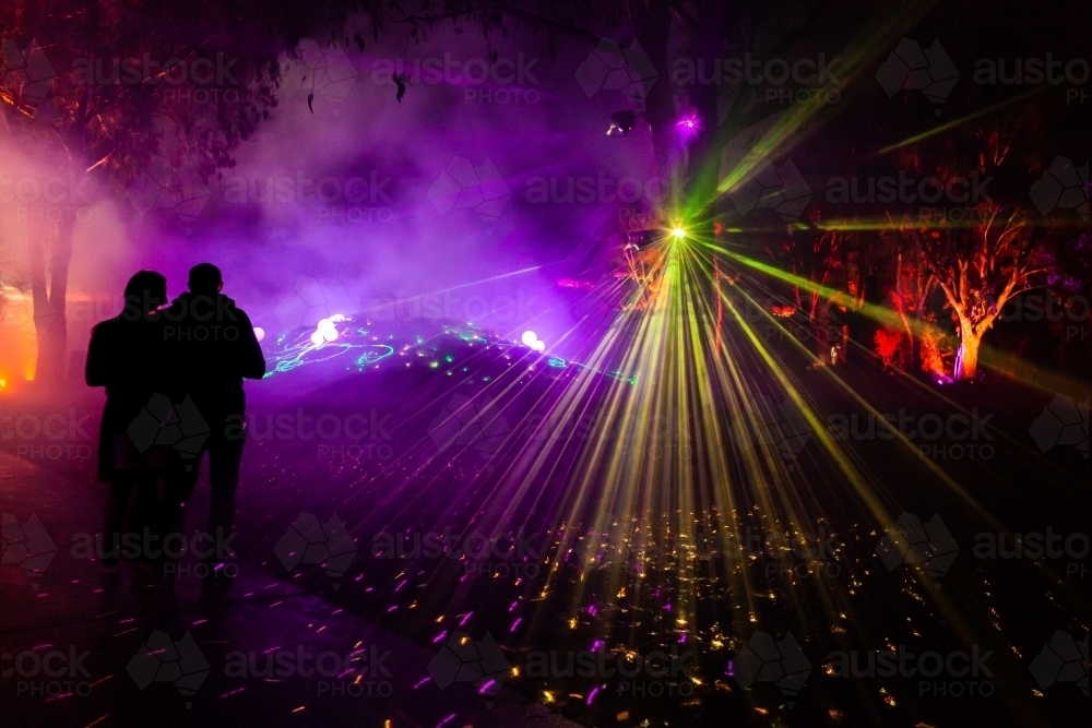 Night time laser light display with beams of colourful light shining through fog - Australian Stock Image