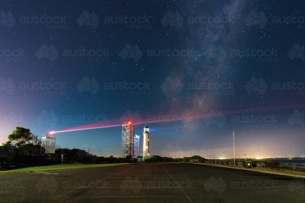 Night time scene of The Milky Way in a starry sky over a lighthouse and beacon towers - Australian Stock Image