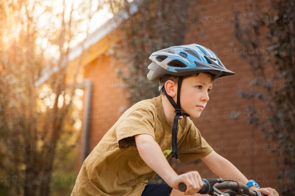 Nine year old boy riding his bicycle at home with helmet on - Australian Stock Image